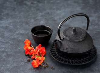 Obraz na płótnie Canvas Black iron asian style teapot and cup green tea and flowers