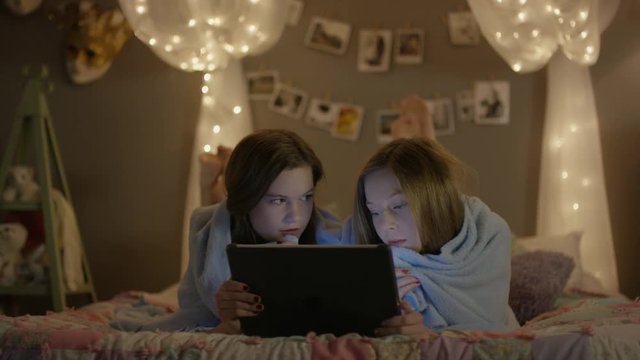 Medium shot of teenage girls watching scary movie at sleepover / Cedar Hills, Utah, United States