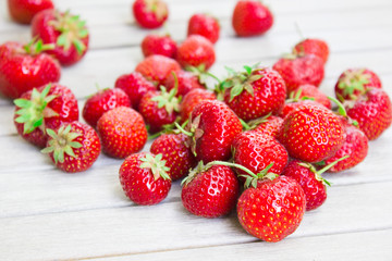 Fresh beautiful strawberries lies on a white wooden table.