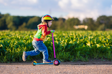Little boy riding a colorful scooter