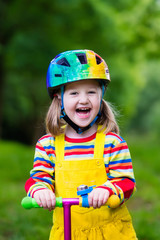 Little girl riding a colorful scooter