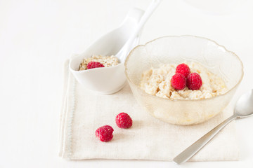 Oatmeal porridge with raspberries on bright wooden table