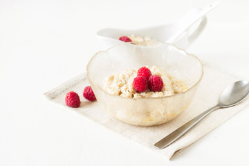 Oatmeal porridge with raspberries on bright wooden table