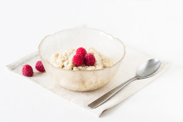 Oatmeal porridge with raspberries on bright wooden table