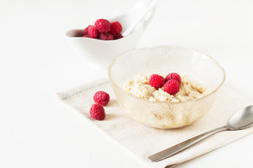 Oatmeal porridge with raspberries on bright wooden table