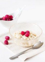Oatmeal porridge with raspberries on bright wooden table