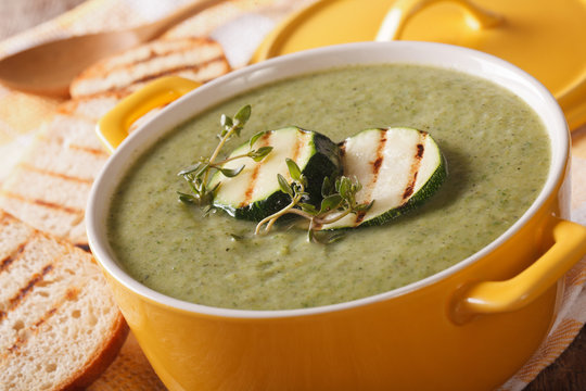 Cream soup of zucchini with herbs close-up in a saucepan. horizontal
