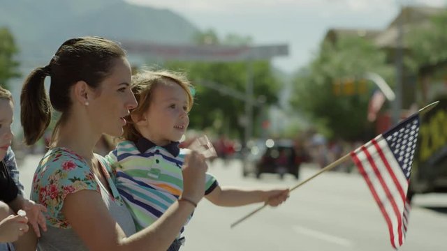 Close up slow motion shot of family watching parade / American Fork, Utah, United States