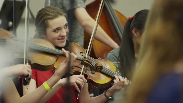Medium shot of teenage girls playing violins in orchestra practice / American Fork, Utah, United States