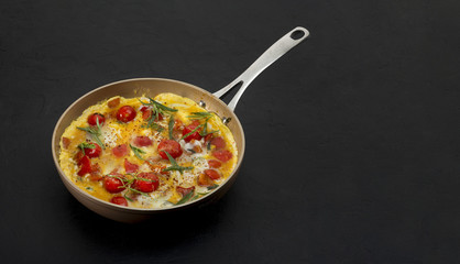 Omelette with tomatoes, and herbs on black background