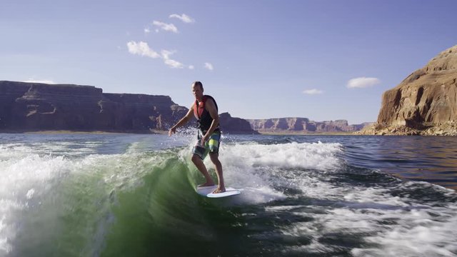 Wide slow motion shot of man surfing in churning water / Lake Powell, Utah, United States