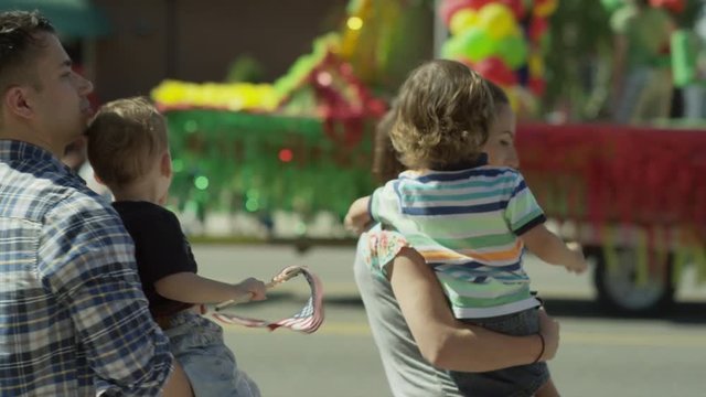 Medium slow motion shot of family watching parade / American Fork, Utah, United States