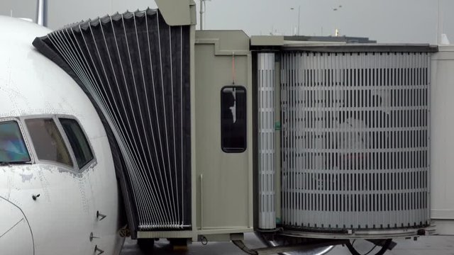 Passengers leaving a plane through jet bridge. People are seen through the jet bridge window. Shot in 4k