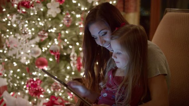 Medium shot of mother and daughter using digital tablet at Christmas / Cedar Hills, Utah, United States