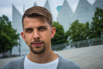 Young man with modern haircut with Philharmonic Hall in Szczecin in the background