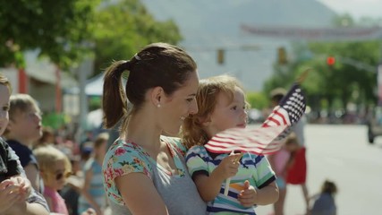 Medium slow motion shot of family watching parade / American Fork, Utah, United States
