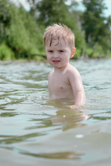 Boy swims in the lake in the summer