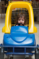 little girl sitting in the children's machine