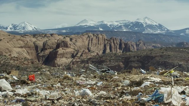 Wide panning shot of landfill garbage in mountain range landscape / Moab, Utah, United States