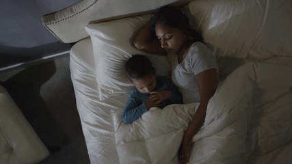 Medium high angle shot of mother and son sleeping in bed / Cedar Hills, Utah, United States
