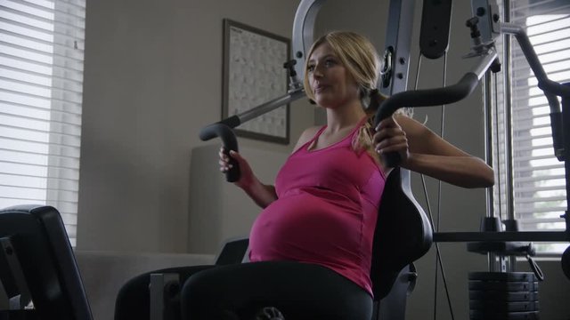 Low angle medium slow motion shot of pregnant woman lifting weights / Cedar Hills, Utah, United States