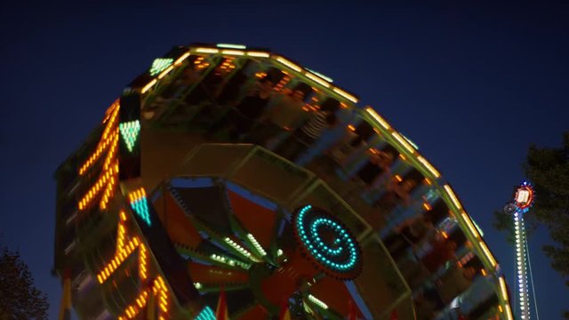Low angle medium slow motion shot of glowing amusement park rides / Pleasant Grove, Utah, United States