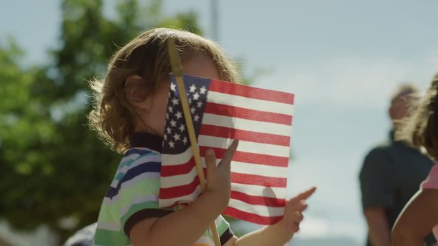 Low angle close up slow motion shot of boy waving American flag at parade / American Fork, Utah, United States