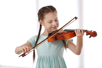 Little girl playing violin on light background © Africa Studio