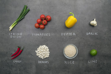 Flat lay food ingredients and vegetables with chalky signs on grey kitchen table.