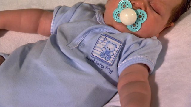 Sleeping baby boy with pacifier in mouth