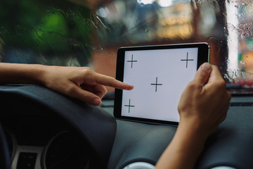 woman looking something on tablet sitting in the car on a rainy day