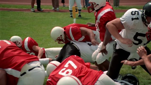 Opposing football players crashing into each other and falling down