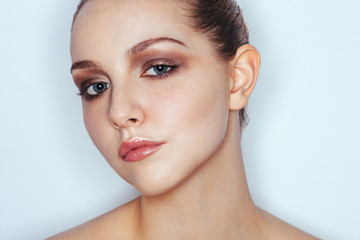 Glamour close up portrait of young beautiful woman model with trendy makeup. Fashion shiny highlighter on skin, sexy gloss lips make-up and dark eyebrows.