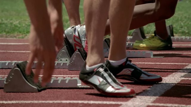 Close-up feet and legs of runners at starting line, slow motion