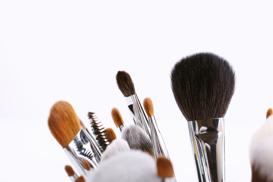Set of various makeup brushes on white background.