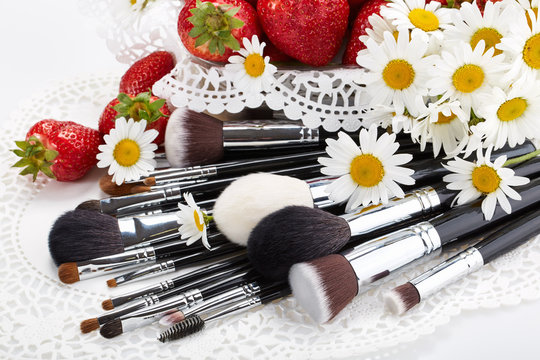 Set of makeup brushes with strawberries and flowers.