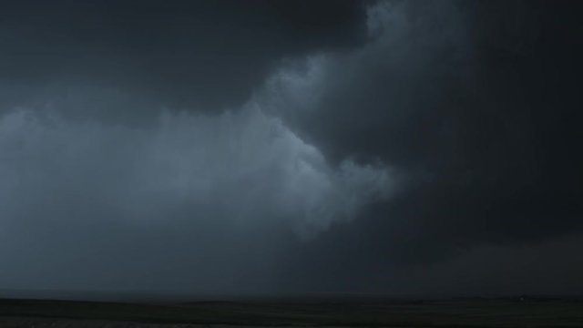 Heavy dark wall cloud dropping a curtain of rain over prairie, time lapse