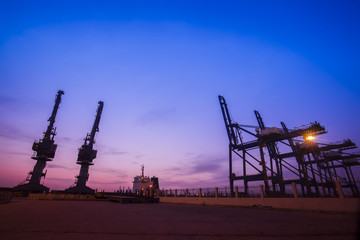 Fototapeta na wymiar Cargo port in the evening，The silhouette of gantry crane