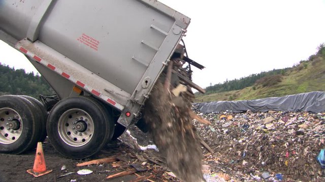 Construction waste pours out of garbage truck