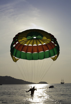 Two people parasailing (silhouette) over the ocean.