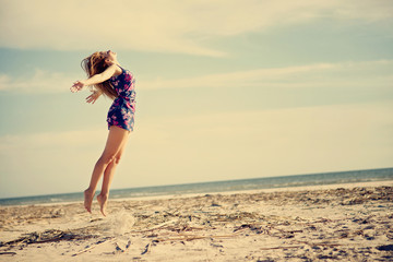 Beautiful young woman jumping at the beach