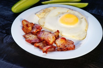 Fried egg with bacon and sliced cucumber