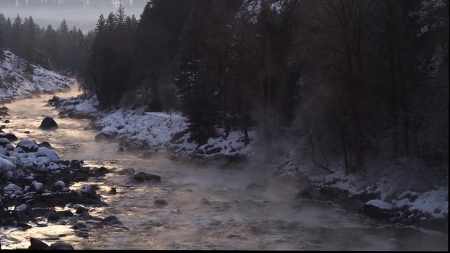 Left pan across a misty fast-flowing river on a wintry evening