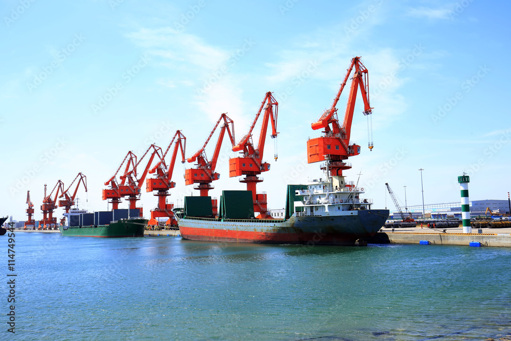 Wall mural in freight terminal, gantry crane and cargo ships are in loading