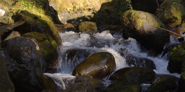 Close view of stream cascading between small boulders