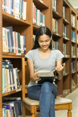 Portrait of a serious young student reading a book in a library