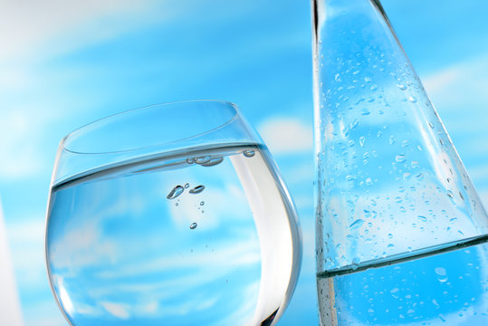 Fresh and clean drinking water in bottle and glass on sky background