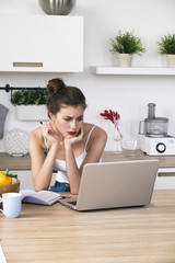 Portrait of housewife at table with laptop in kitchen