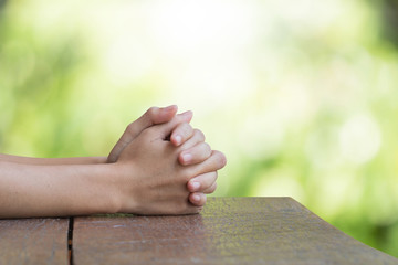 Hands on an old wooden table Natural background blurred bokeh pretty bright. Prayer to God