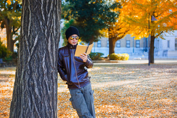 An Asian Man Stands under a Yellow Ginkgo Tree in Autumn